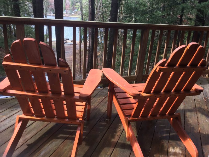 Two Adirondack chairs on the deck with the lake beyond