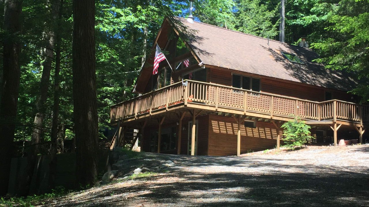The whole chalet from outside, with its wraparound deck and a flag