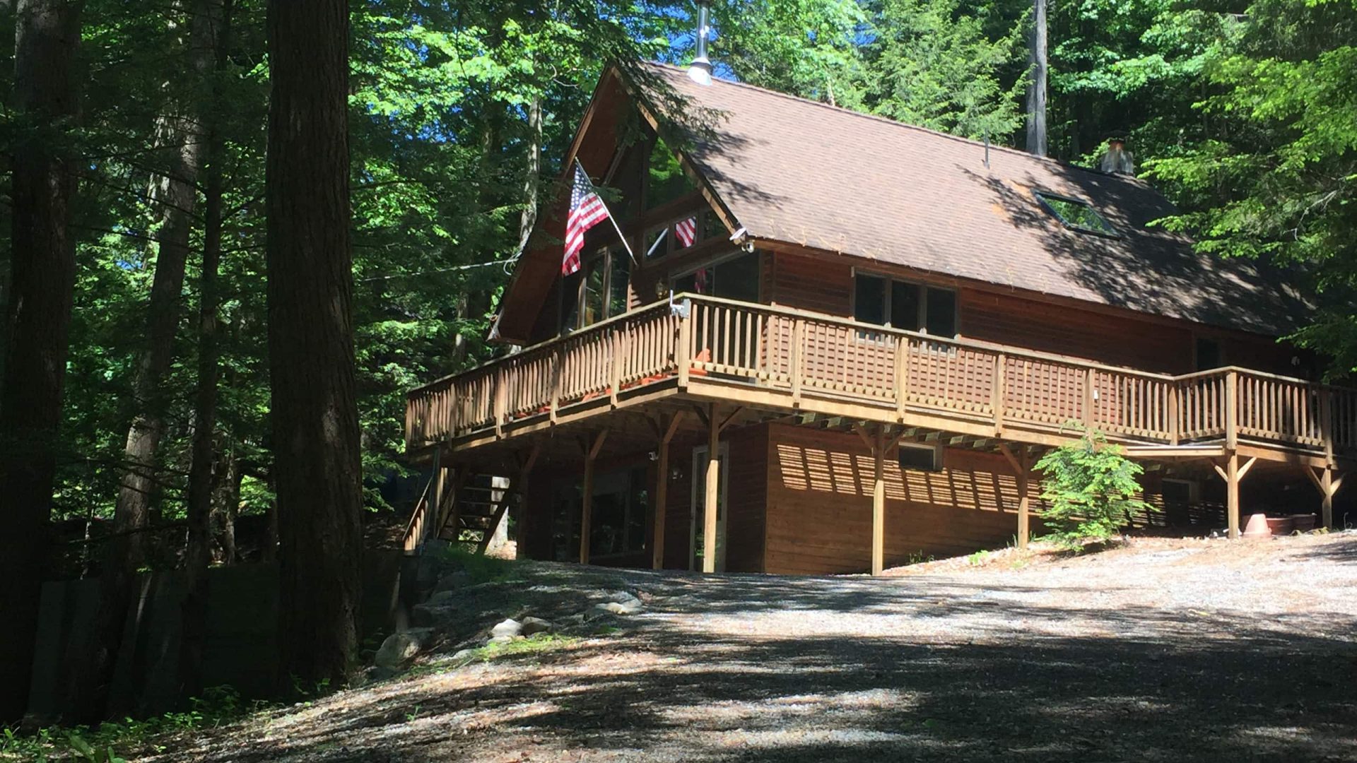 The whole chalet from outside, with its wraparound deck and a flag