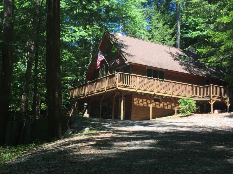 The whole chalet from outside, with its wraparound deck and a flag