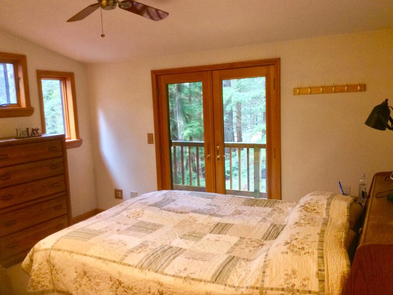 Top-floor master bedroom with a ceiling fan and French doors to the private deck