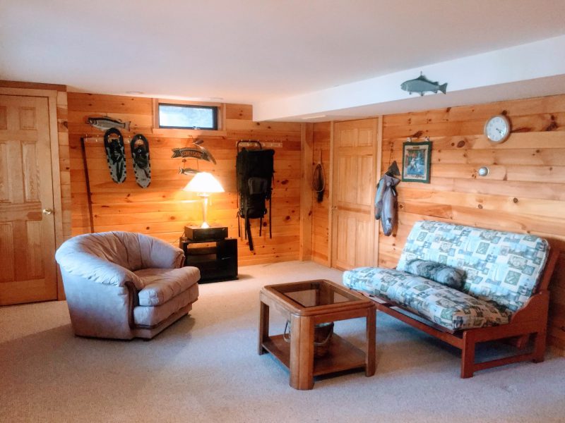 Ground-floor den with a futon and knotty pine walls
