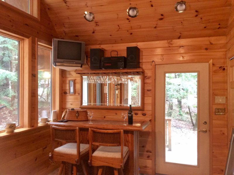 Bar area with stools, a TV and wine glasses