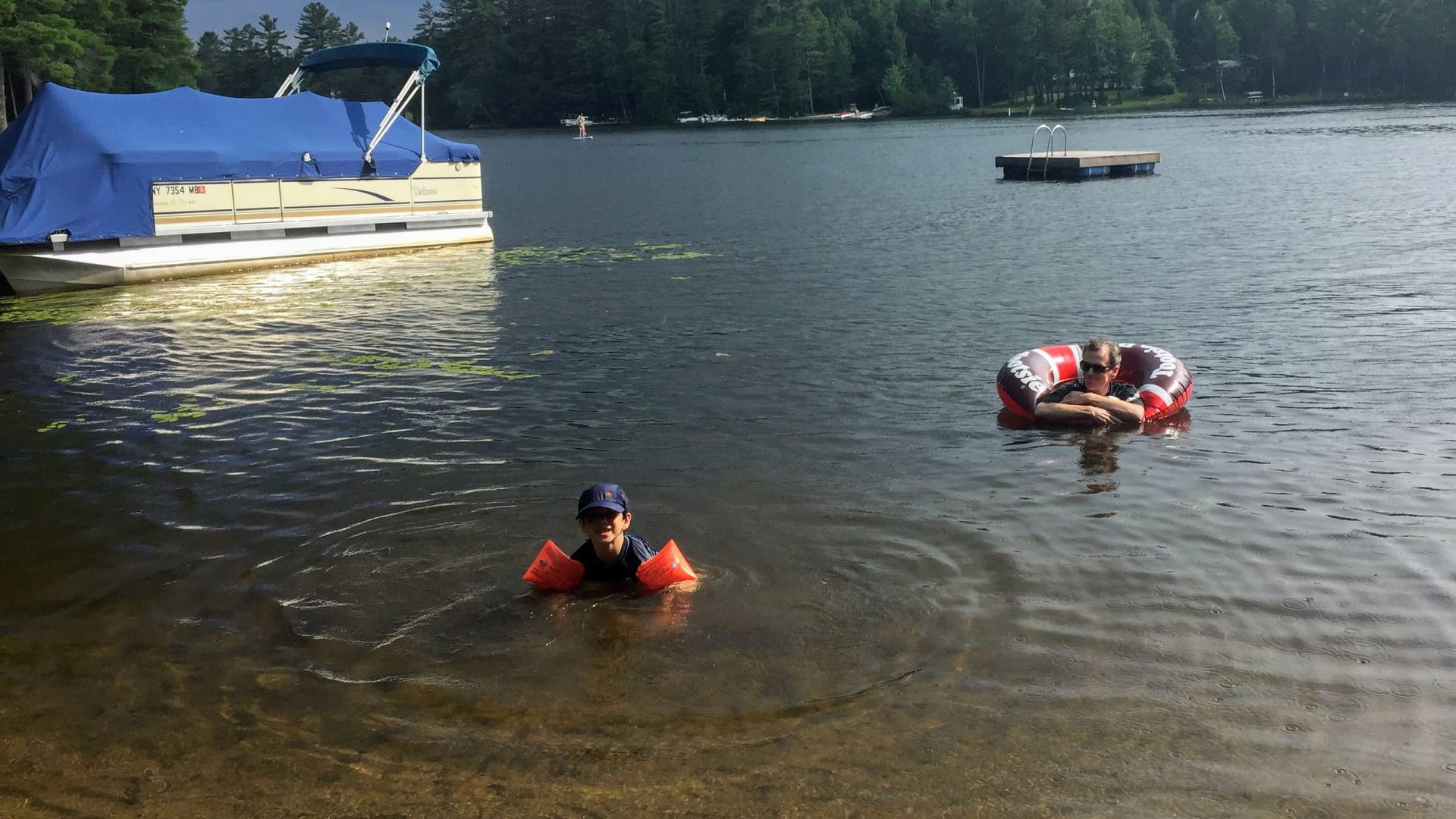 Swimmers, a pontoon boat and an inner tube on the lake