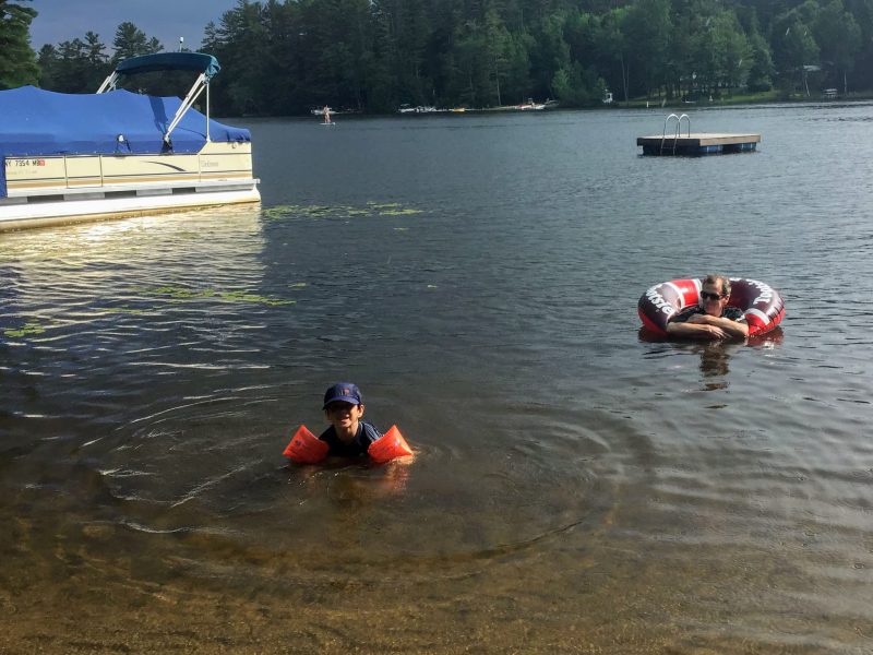 Swimmers, a pontoon boat and an inner tube on the lake