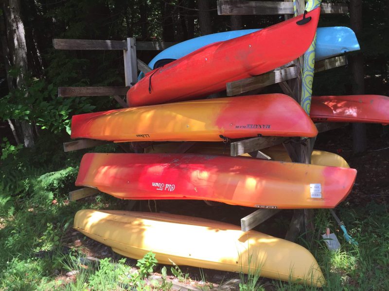 Colourful kayaks and a canoe on the boat rack